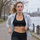 Runner mid-interval by a river with a Polar H10 chest strap worn on bare skin under an open jacket and a sports watch on her wrist