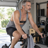 Man riding a bike on a trainer in a home gym, wearing a Polar H10 chest strap