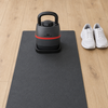 High-angle view of a Bowflex SelectTech 840 kettlebell standing in its base on an exercise mat, with a pair of trainers beside the mat for scale