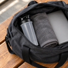 Closed BlenderBottle Classic V2 packed in an open gym bag next to a rolled towel and a laptop