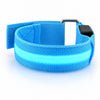 A blue LED armband on a white background, its centre strip lit blue, with a hook-and-loop strap, a metal loop and a small black button unit.
