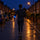 A runner on a dark residential street seen from behind, a blue LED armband glowing evenly along its length on the forearm