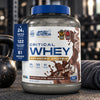 Applied Nutrition Critical Whey 2kg Chocolate Milkshake tub on a gym floor