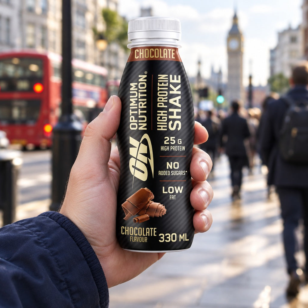 A hand holding an Optimum Nutrition High Protein Shake 330ml bottle on the go