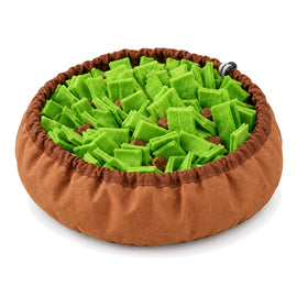 A round snuffle bowl on a white background, with a brown fabric rim and a bed of green felt strips hiding pieces of dry food.
