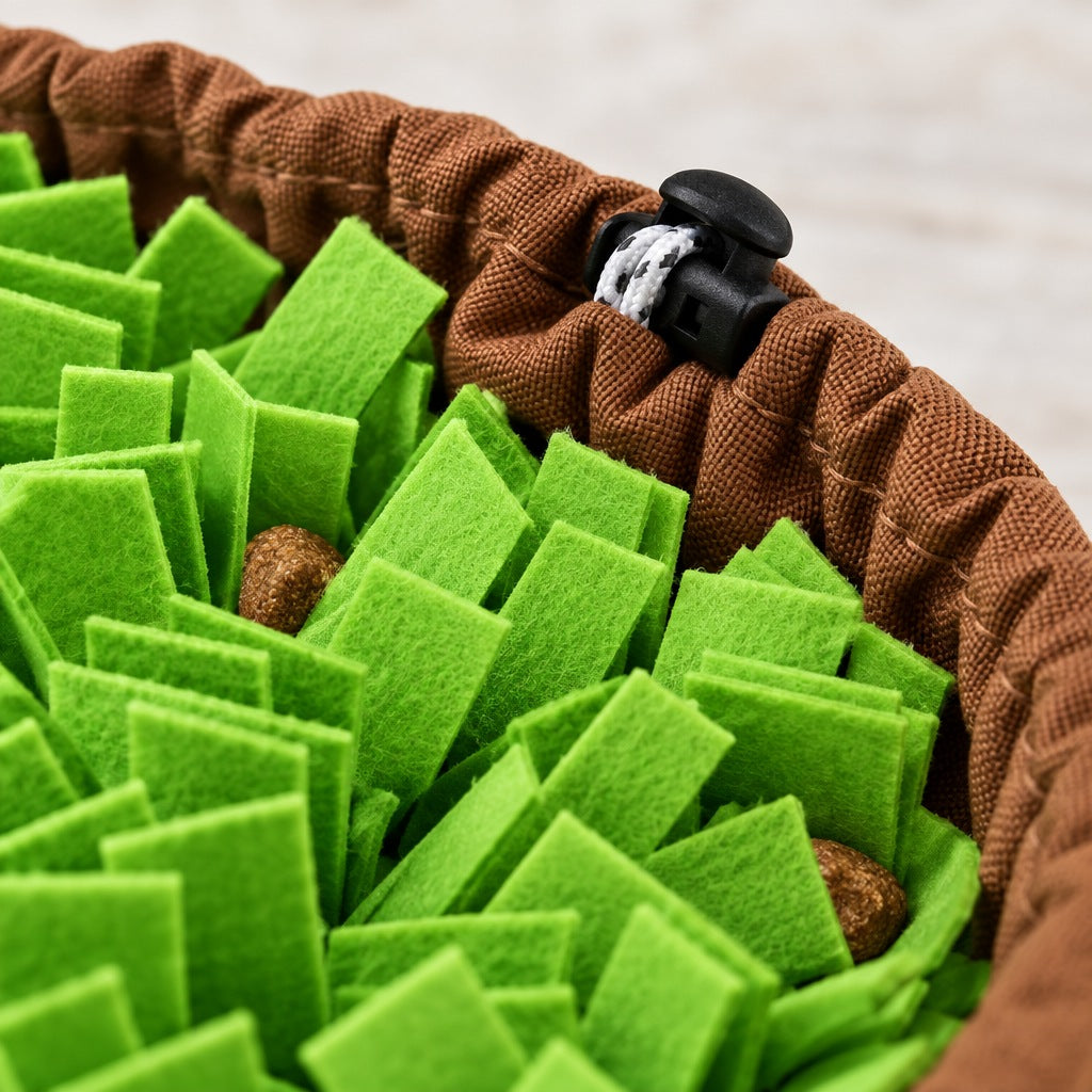 Close-up of the green felt strips, a piece of kibble tucked between them, and the gathered brown rim with its black cord toggle.