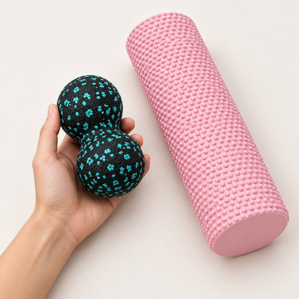 Foam roller and peanut massage ball beside a hand to show size