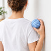 Spiky massage ball between the upper back and a wall