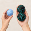 Spiky massage balls and peanut ball beside a hand to show size