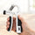 An older hand holding the white grip trainer by its black handles over a light wooden table