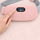 A finger pressing the button on the pink heated period belt, with the heat setting shown on the digital display