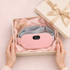 The pink heated period belt in an open gift box with pink tissue paper and a cream ribbon